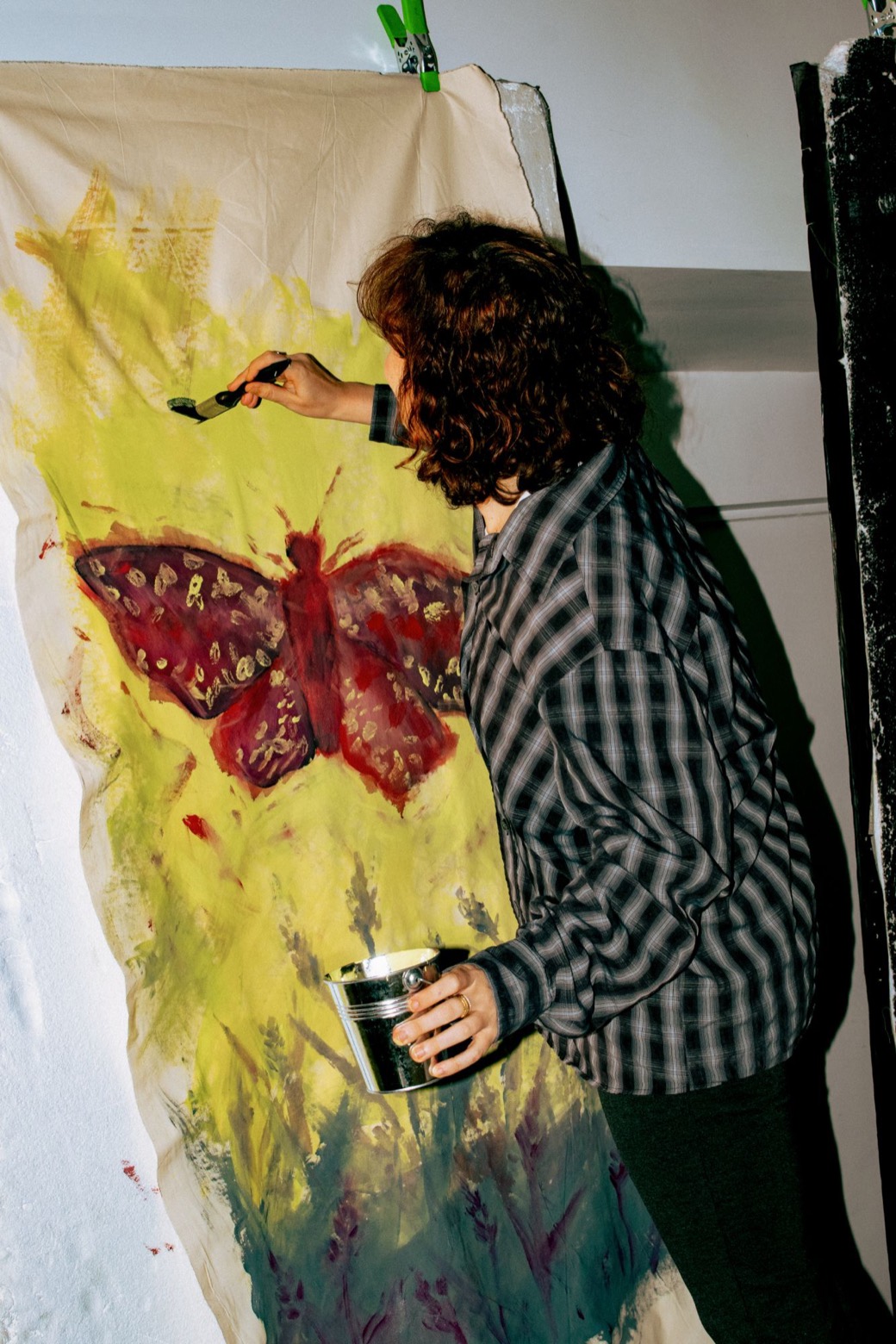 A moth painted in deep red and gold on a yellow length of calico, being worked on at Session 01, Green Hour, in London