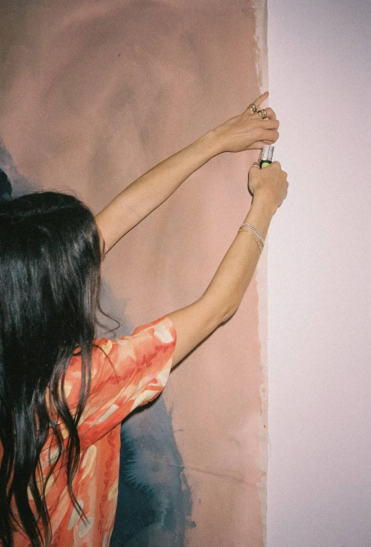 A woman taking her painted length down from the wall at the end of a painting evening in London for women