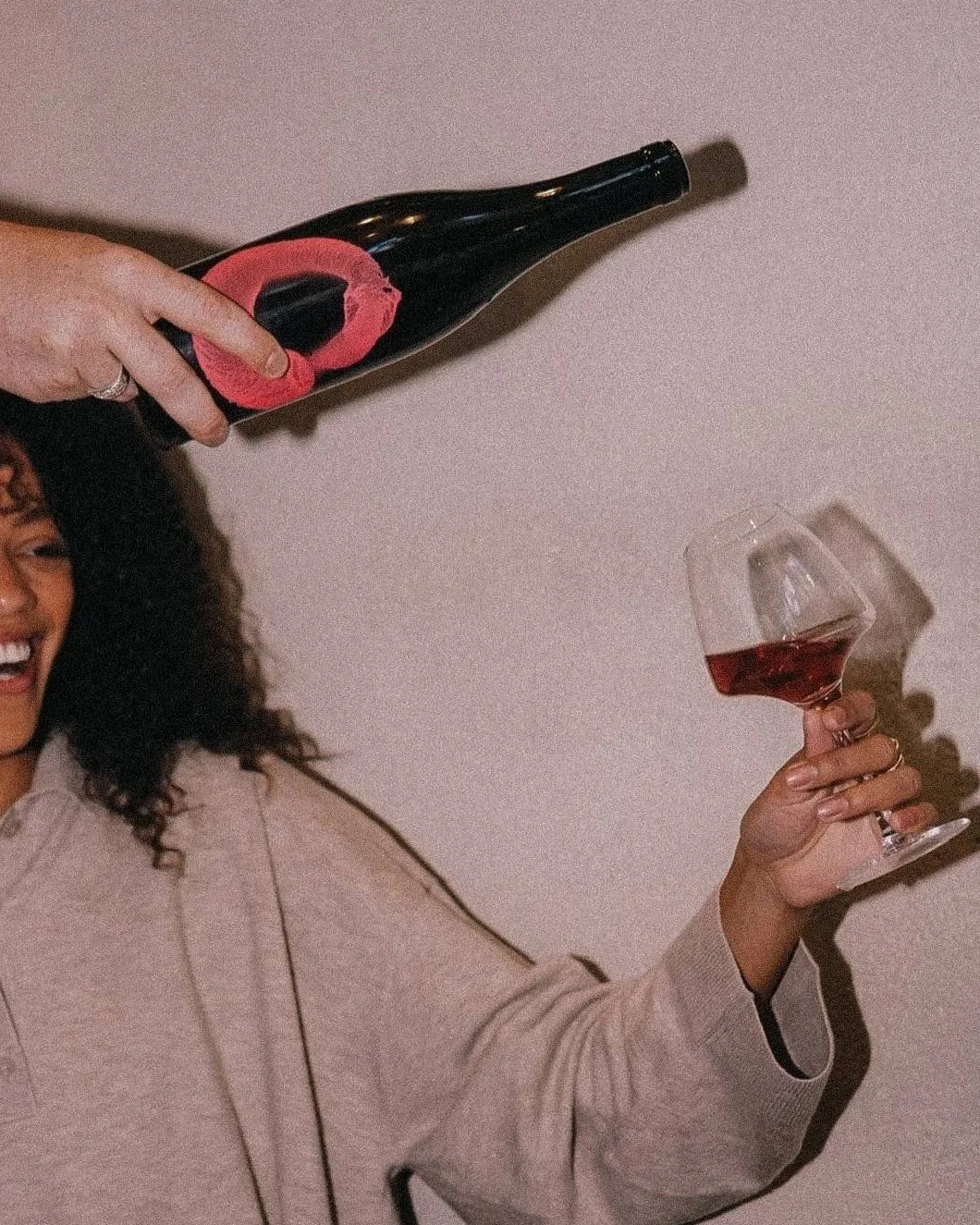 A glass of wine raised and a bottle poured at the salon that ends a painting evening in London for women